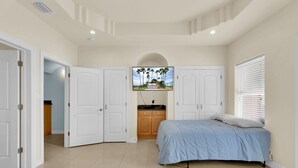 Ein Schlafzimmer mit einem Bett, einem Kleiderschrank und einem Fernseher an der Wand.