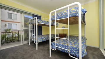 A room with bunk beds, a small table, and a window with a view of a building.