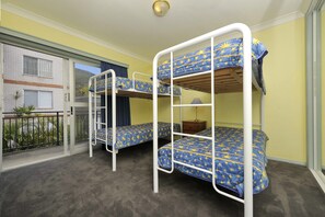 Een kamer met stapelbedden, een klein tafeltje en een raam met uitzicht op een gebouw.