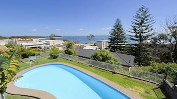 A swimming pool with a view of the sea and buildings in the background.