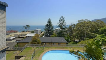 A residential area with a swimming pool, a view of the sea, and a mountain in the distance.