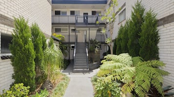 A multi-level building with a central staircase, surrounded by various plants and shrubs.