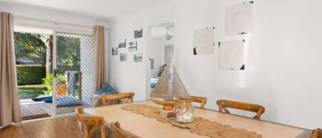 A dining area with a wooden table, four chairs, and a view of a garden through a glass door.