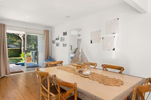 A dining area with a wooden table, four chairs, and a view of a garden through a glass door.