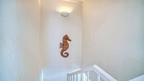 A staircase with a wall-mounted light fixture and a decorative seahorse. - LaPlaya 204D-Beach-lovers paradise! (Longboat Key)