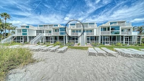 Um hotel moderno à beira-mar, com vários andares, área de piscina, espaço para sentar ao ar livre e escadaria que leva à entrada.