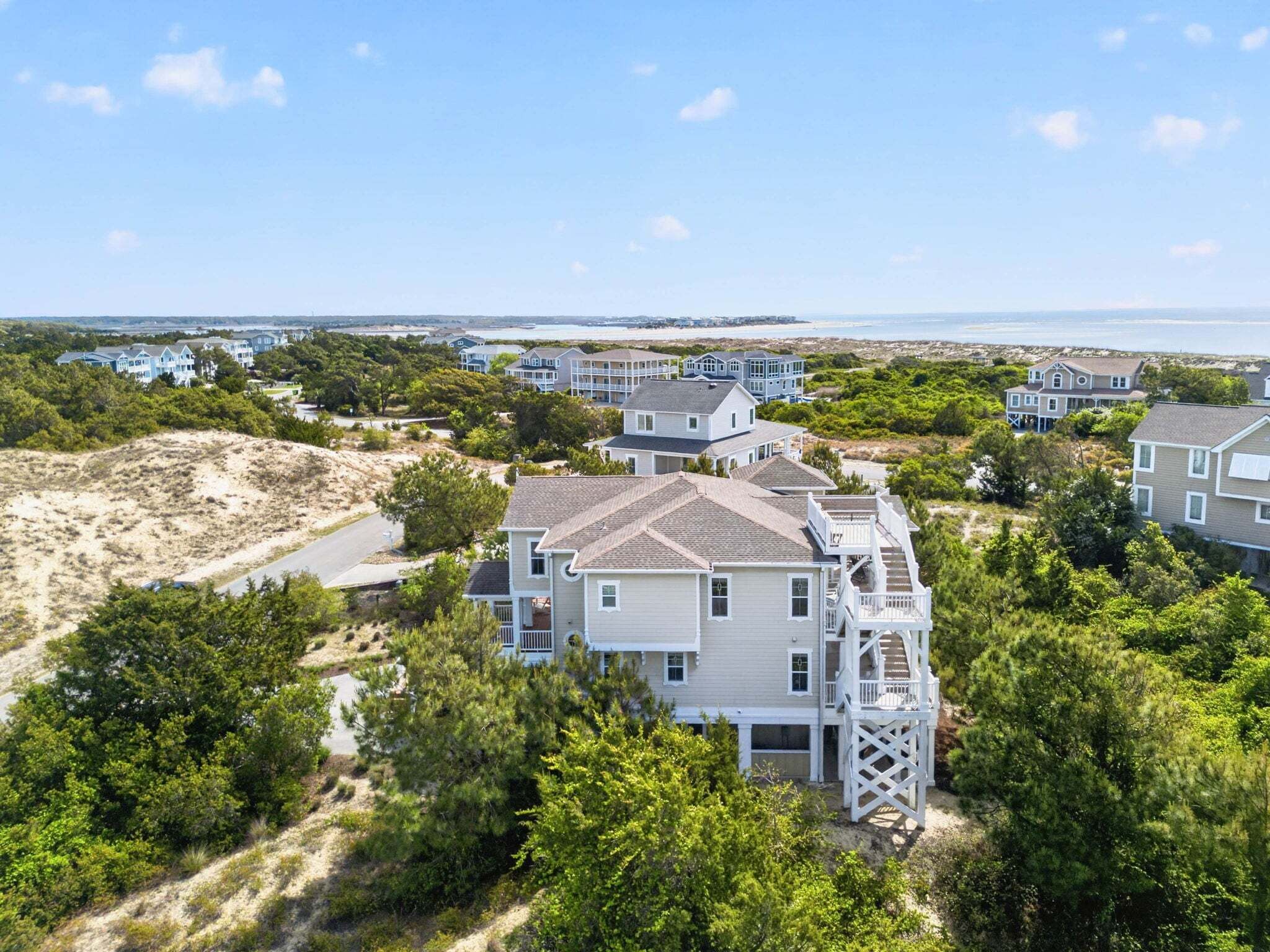A coastal residential area with houses, a sandy beach, and a view of the ocean.