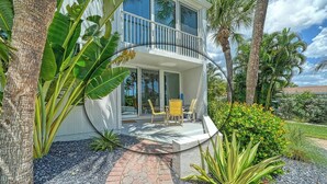 A two-story house with a balcony, surrounded by tropical plants and palm trees. - LaPlaya 101E-Relax on your private lanai under the palms! (Longboat Key)
