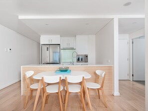 Een moderne keuken met een centraal eiland, witte kasten en een roestvrijstalen koelkast.