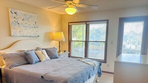 A bedroom with a bed, a ceiling fan, a window with blinds, and a painting on the wall. - Dry Dock / 150 Tarpon: Spacious 4-bedroom home in Holden Beach with canal views. (Holden Beach)