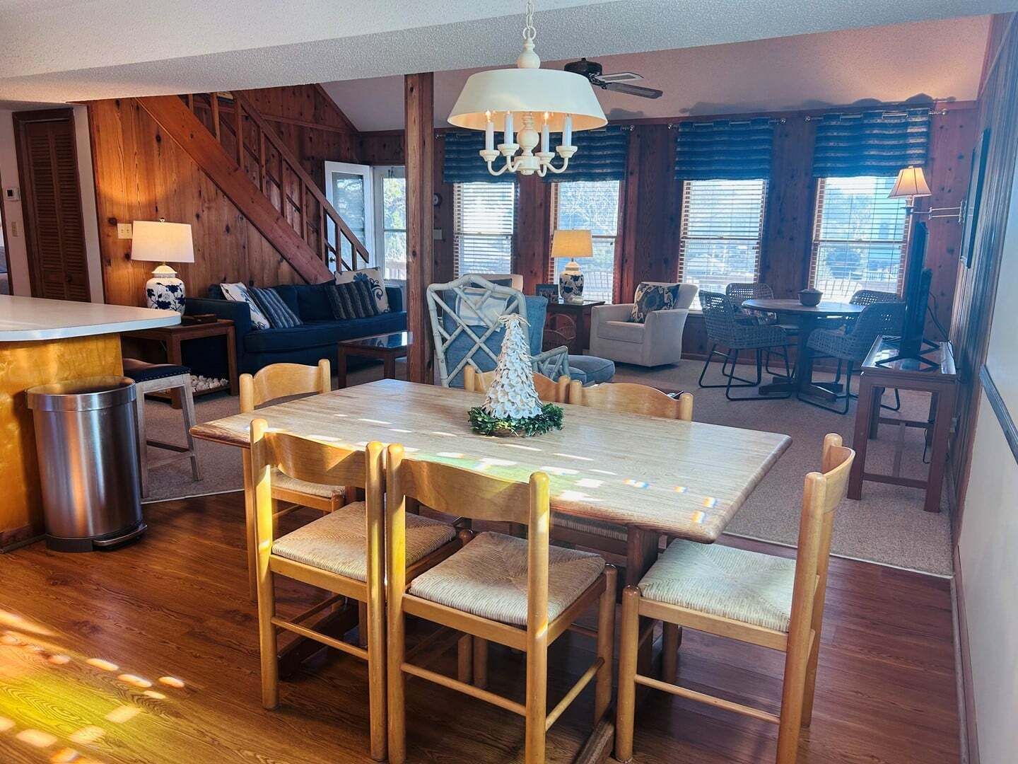 Ein Essbereich mit Holztisch und -stühlen, einer Chandelüster und einer Treppe im Hintergrund.