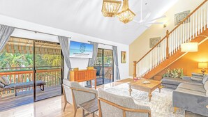 Ein geräumiges Wohnzimmer mit Balkon, einer Holztreppe und einem Deckenventilator.