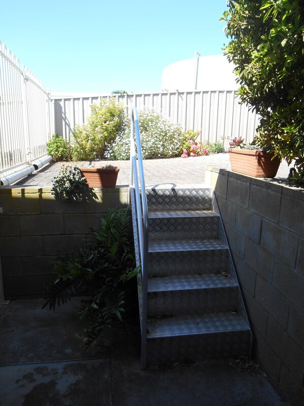 A set of outdoor stairs leading up to a rooftop area with potted plants and a white fence. - Edith's Magnificent Views Dog friendly Off Peak Special! (Point Turton)