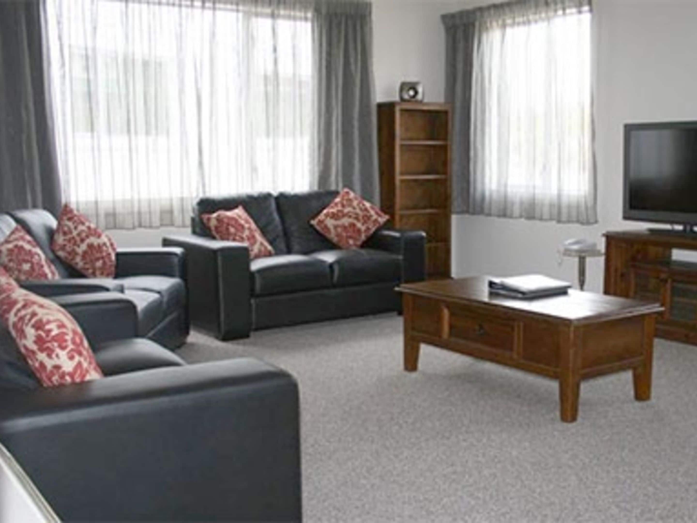 A living room with a sofa set, a coffee table, a TV, and a bookshelf.