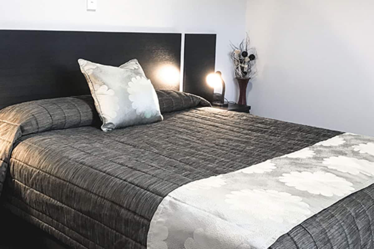 A neatly made bed with a dark headboard, a floral-patterned bedspread, and two bedside lamps.