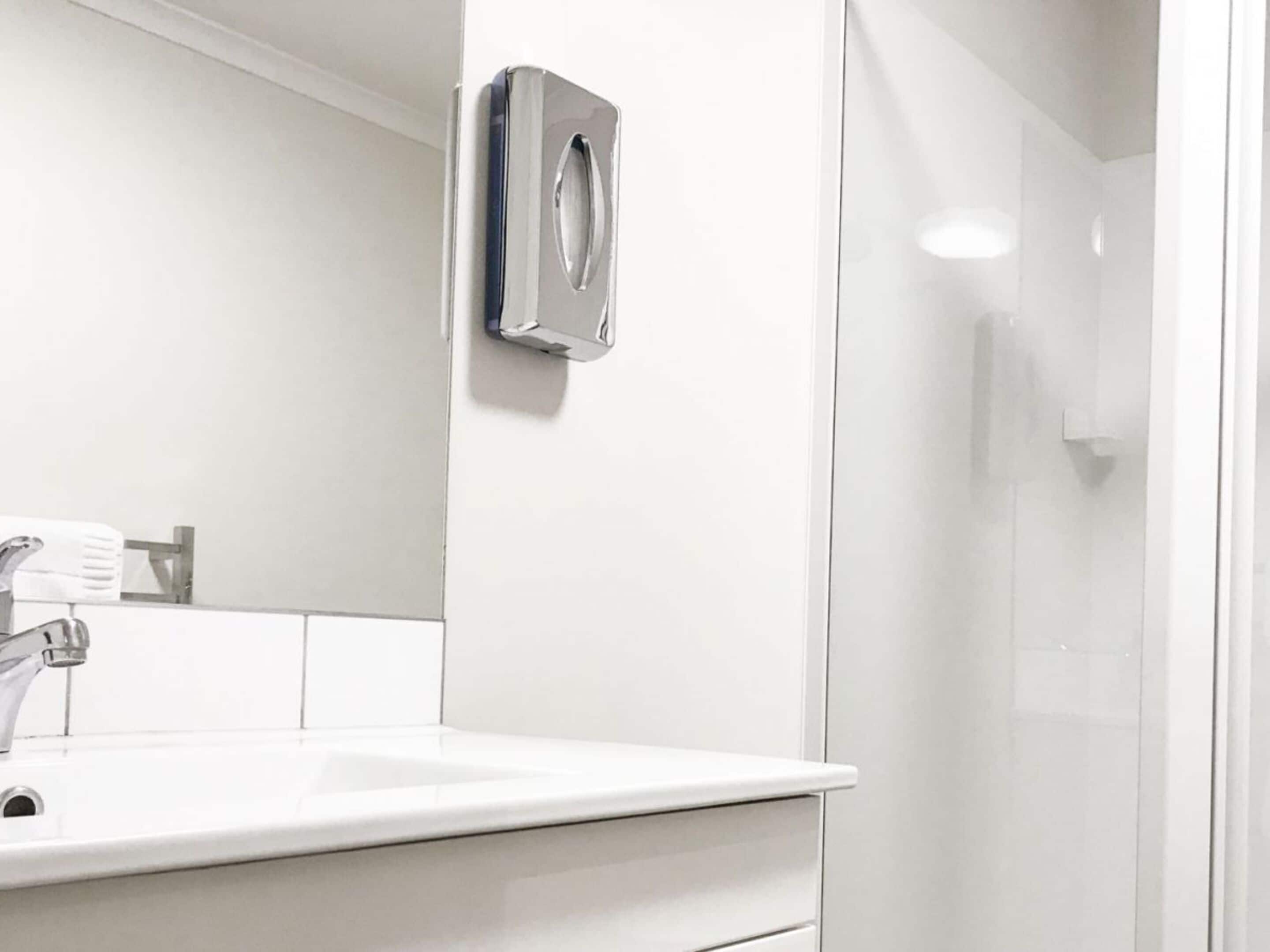 Une salle de bain moderne avec un lavabo blanc, un miroir et une cabine de douche en verre.