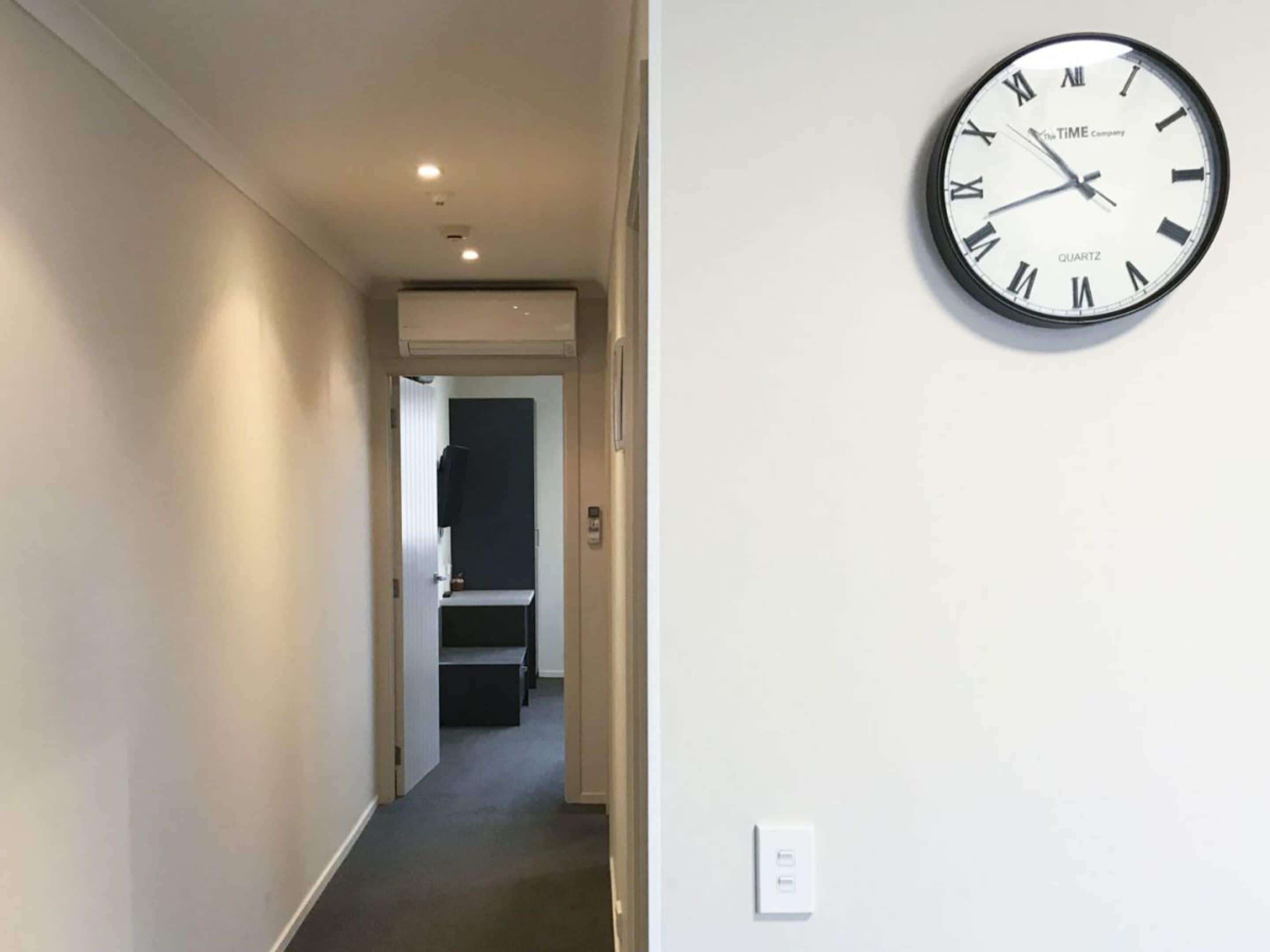 A hallway with a wall-mounted clock displaying 10:42.