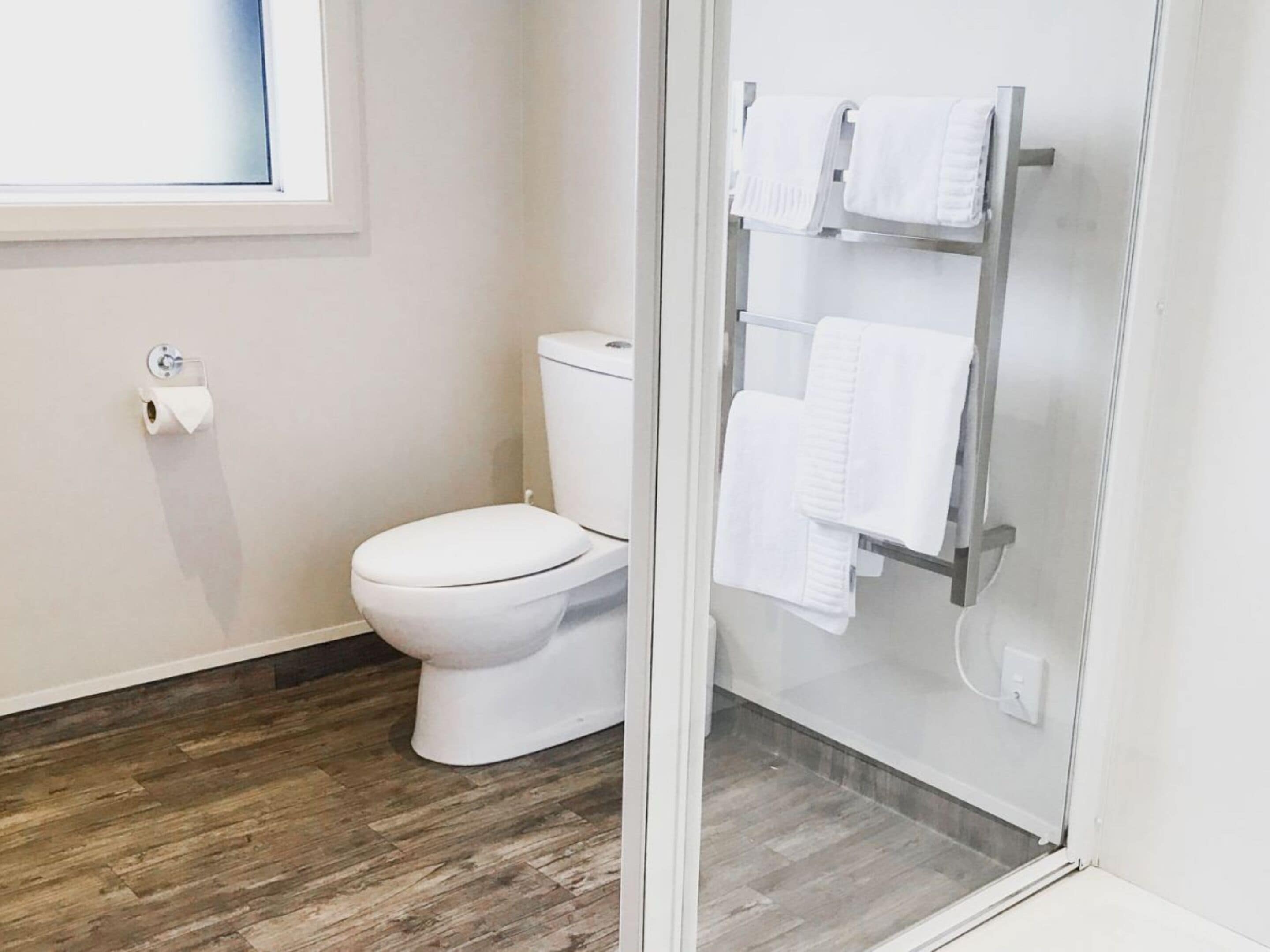 Un baño moderno con inodoro, toallero y dispensador de papel higiénico.