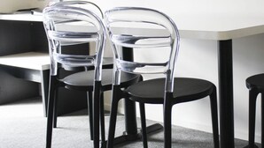 A modern office space with two transparent chairs and a black desk.