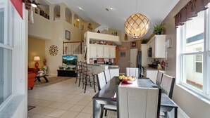 A spacious living area with a dining table, kitchen, and a large window providing natural light. - 6BR Pool Home Windsor Palms by SHV-2238 (Kissimmee)