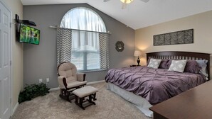 A bedroom with a bed, a chair, a desk, a ceiling fan, a TV, and a window with curtains. - 6BR Pool Home Windsor Palms by SHV-2238 (Kissimmee)