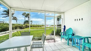 Une terrasse couverte avec vue sur la plage, des sièges d’extérieur et une porte donnant sur l’extérieur.