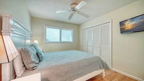 A bedroom with a bed, a ceiling fan, a window, a closet, and a wall-mounted TV. - LaPlaya 109A-Enjoy the balmy breezes in this corner end unit right on the beach. (Longboat Key)
