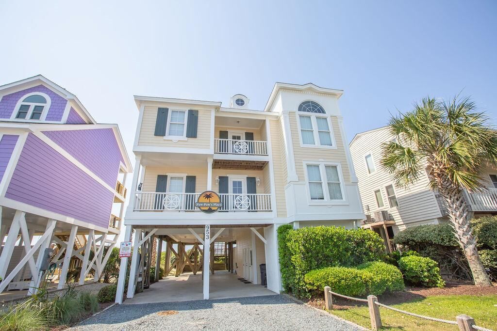 A multi-story building with a balcony, a sign reading "New Bay's Place," and a palm tree in the background.