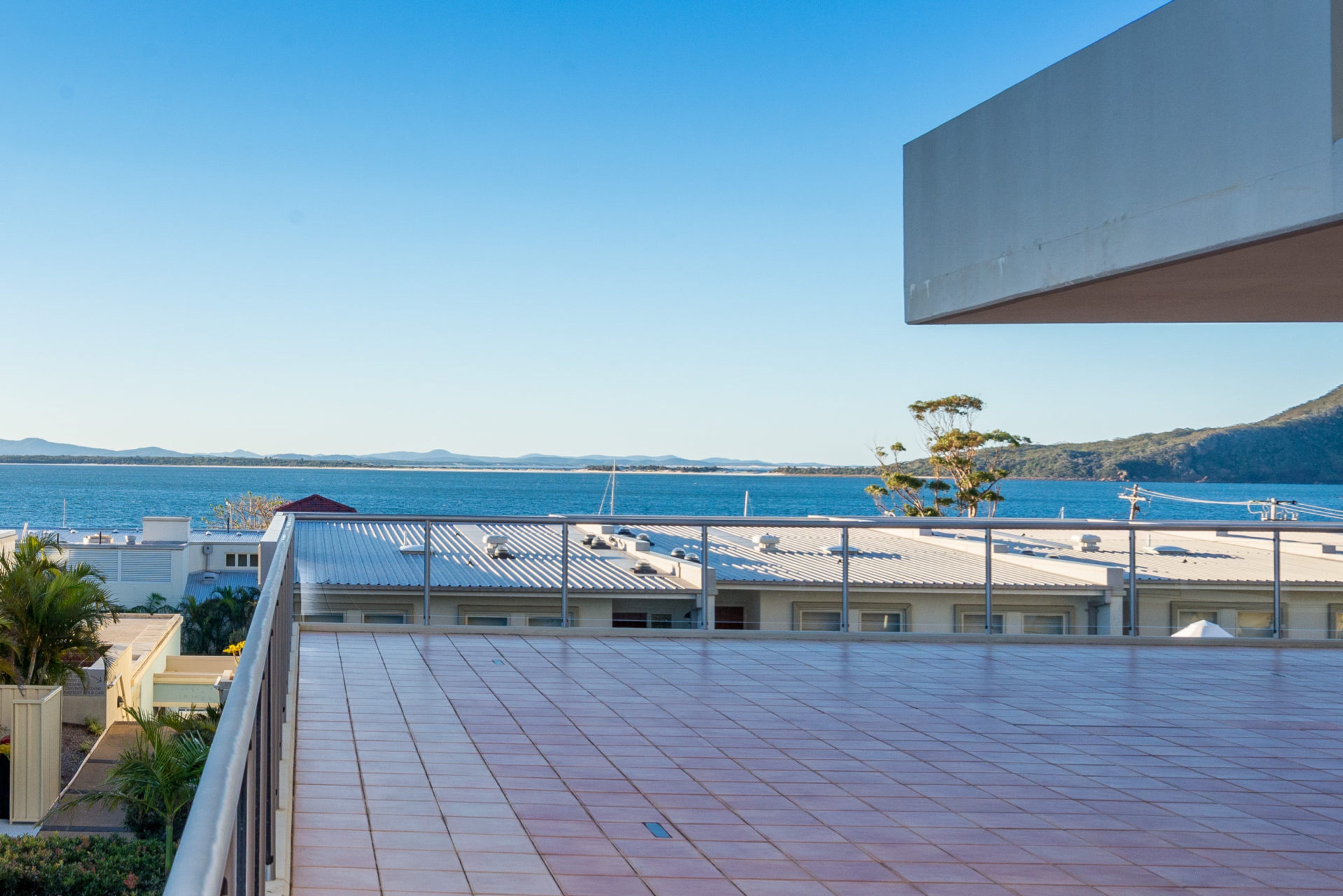 A rooftop terrace with a view of the sea and distant mountains.