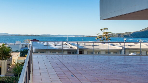Terraço no terraço com vista para o mar e montanhas ao longe.