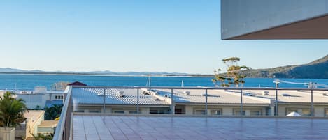 A rooftop terrace with a view of the sea and distant mountains.