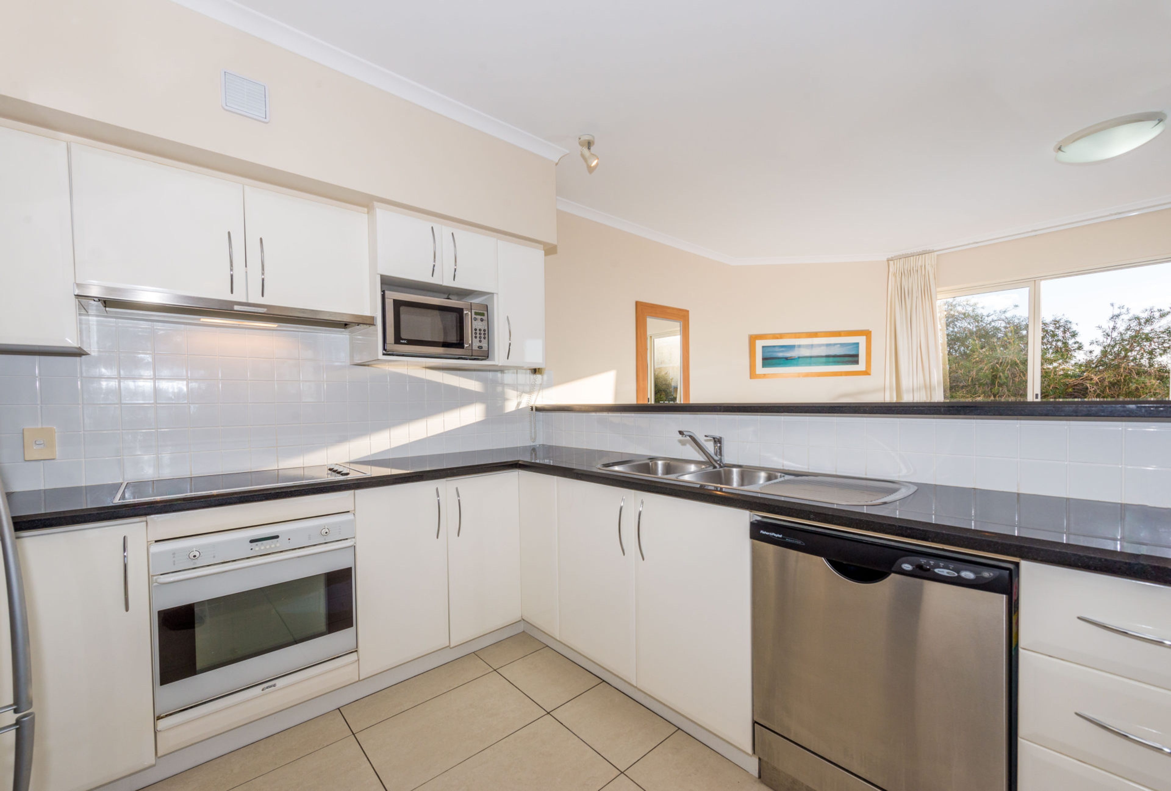 A modern kitchen with white cabinets, a microwave, a dishwasher, and a sink.