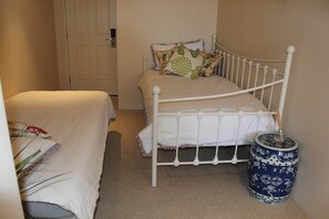 A bedroom with two beds, a white headboard, and a decorative blue and white vase on the floor.
