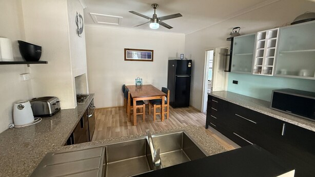 A compact kitchen with a dining table, a refrigerator, a stove, and a ceiling fan.