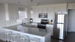Uma cozinha moderna com uma ilha central, eletrodomésticos de aço inoxidável e armários brancos.