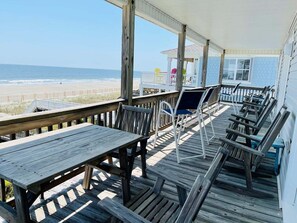 Eine Holzterrasse mit Tischen und Stühlen mit Blick auf den Strand.