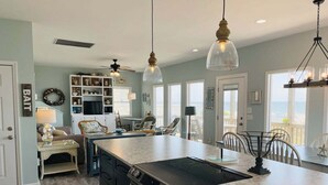 A kitchen with a central island, black appliances, and pendant lighting. - Oceanfront bliss awaits at Our Sand Dune, a spacious 5-bedroom retreat in Holden Beach. (Holden Beach)