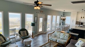 A spacious living area with a view of the ocean, a dining area, and a kitchen. - Oceanfront bliss awaits at Our Sand Dune, a spacious 5-bedroom retreat in Holden Beach. (Holden Beach)