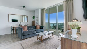 Una sala de estar moderna con un sofá gris, una mesa de centro y un comedor con una mesa y sillas.