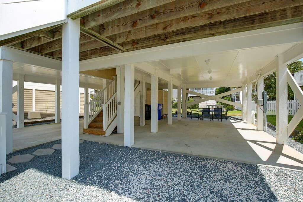 A covered outdoor area with a wooden ceiling, white pillars, and a concrete floor.