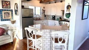A kitchen with white cabinets, a refrigerator, and a dining area with white chairs.