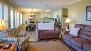 A living room with a sofa, armchair, and a dining area with a table and chairs. - Experience coastal bliss at Holden Haven, a spacious 4-bed retreat in Holden Beach. (Holden Beach)