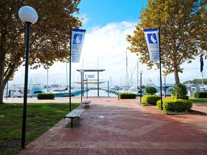 Una passeggiata sul lungomare con panchine, vista chiara sulle barche e striscioni per 'd'Albora Marinas'.