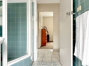 A bathroom with a shower, a towel rack, and a wooden cabinet.