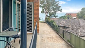 Varanda com vista para o mar, mesa com cadeiras e porta com mosquiteiro.