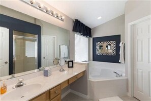 A bathroom with a large mirror, a bathtub, and a vanity with a sink. - 4BR Pool Home Emerald Island by SHV-2659 (Kissimmee)