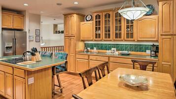 A kitchen with wooden cabinets, a central island with a sink, and a dining area with a table and chairs.