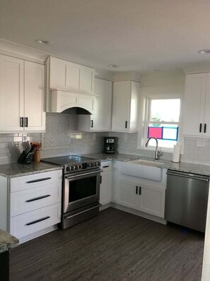 A modern kitchen with white cabinets, a stainless steel stove, and a dishwasher.
