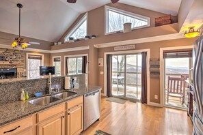 A spacious kitchen with granite countertops, a dishwasher, and a stone backsplash. There is a large window above the sink and a ceiling fan. - Family Home w/ Decks & Sunset Views in Beech Mtn! (Beech Mountain)
