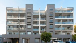 A multi-story residential building with balconies, large windows, and a flat roof. - A modern, Coastal Unit in Shoal Bay! (Shoal Bay)